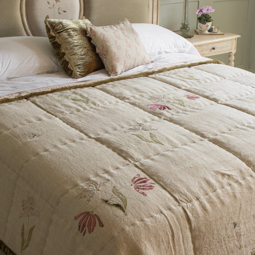 Embroidered tulip sprigs and green velvet trim on the linen quilt