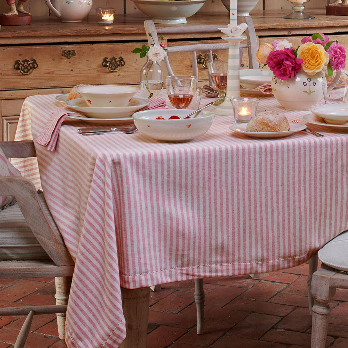 Dining table in the red striped cloth with flowers and a cake
