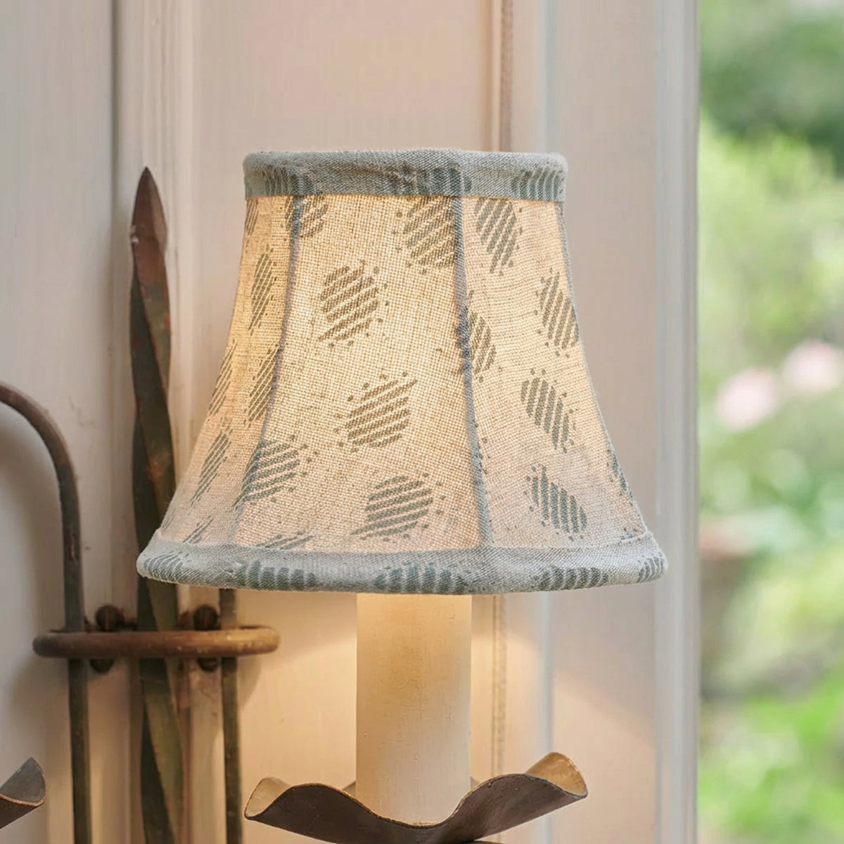 The same blue Nina wall shade lit, glowing warmly against panelling