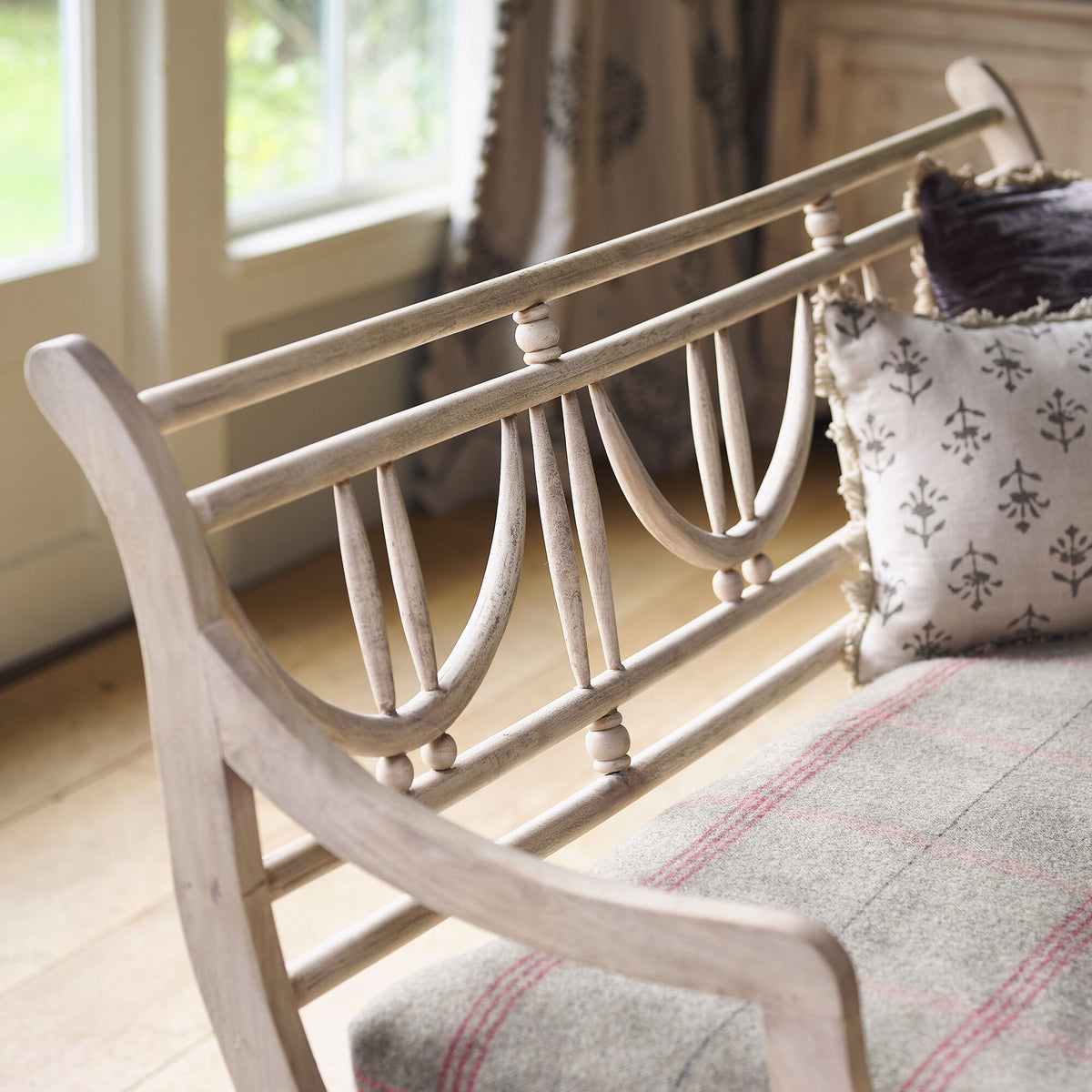 Angled view of the Gustavian bench by a window with cushion