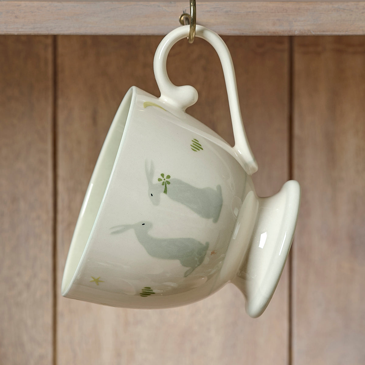 Summer Sitting Hares large mug tipped on its side against wooden panelling