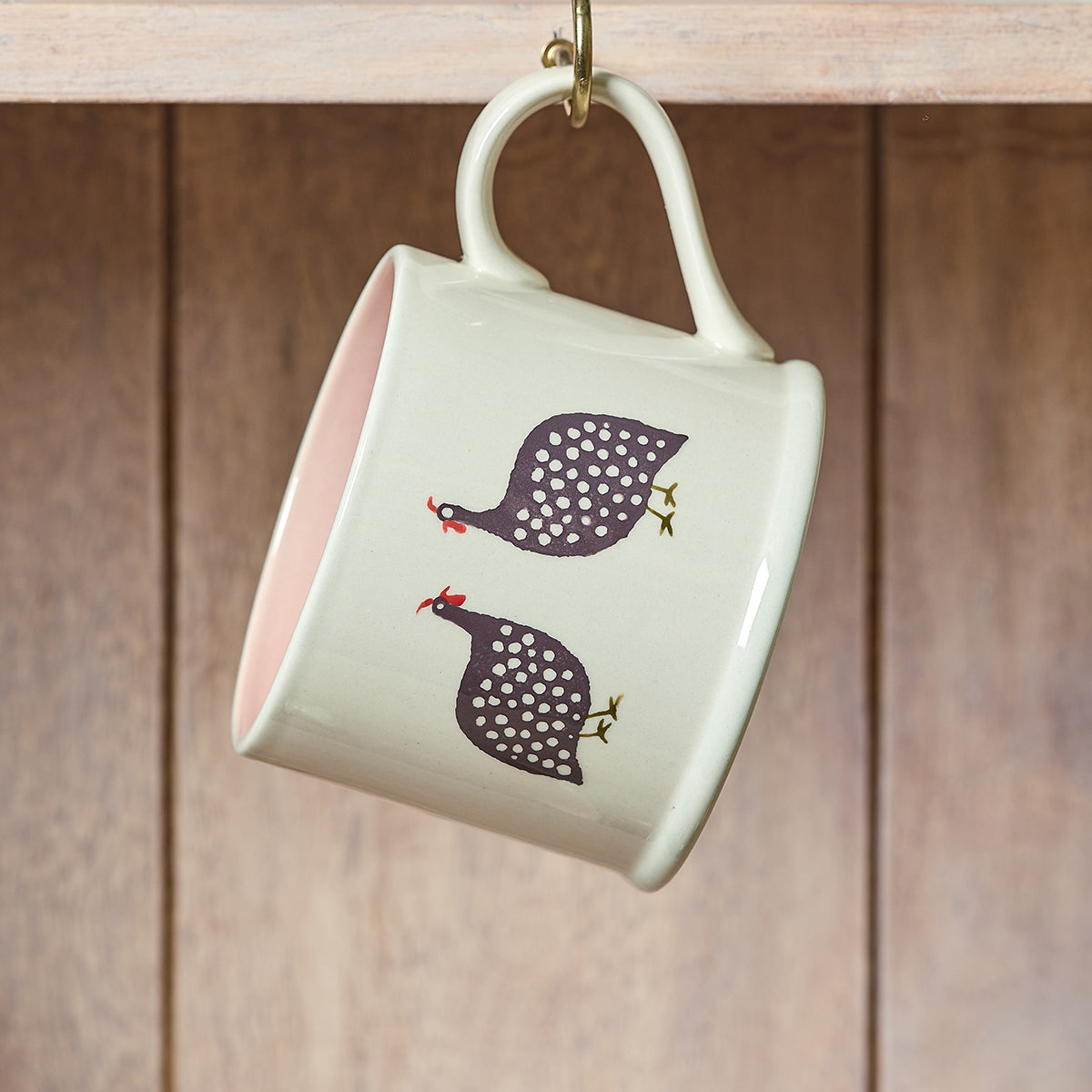 Guinea fowl straight mug hanging from a hook on wooden panelling