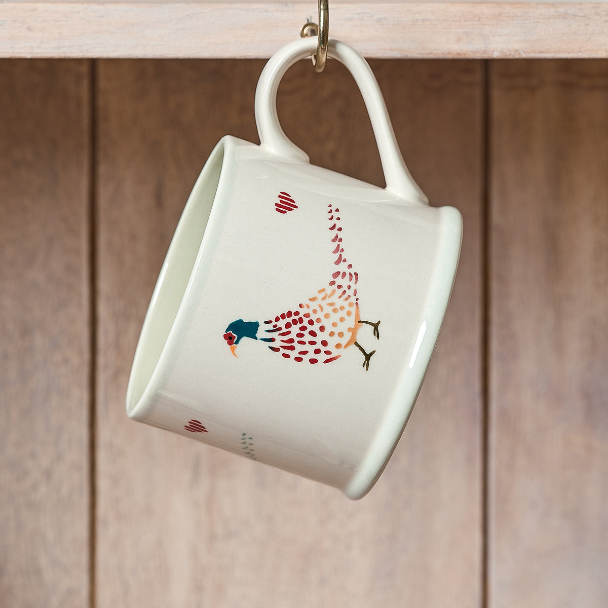Pheasant straight mug tipped on its side against wooden panelling