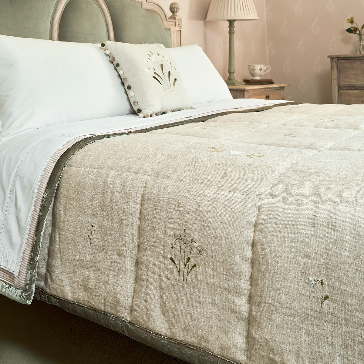 Snowdrop rustic linen quilt on a bed with embroidered sprigs and white pillows