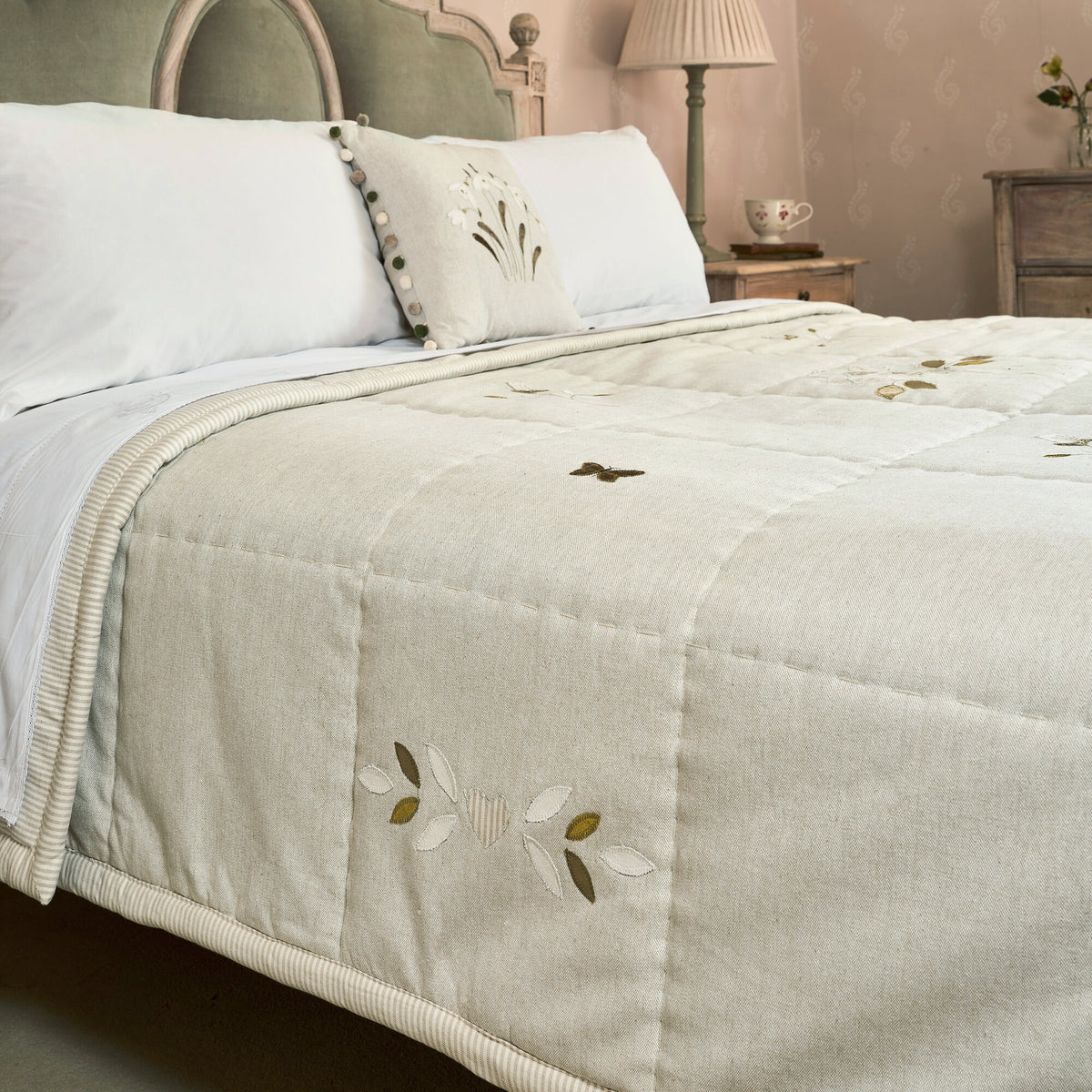 Grey Rose cotton quilt spread across a bed with white pillows