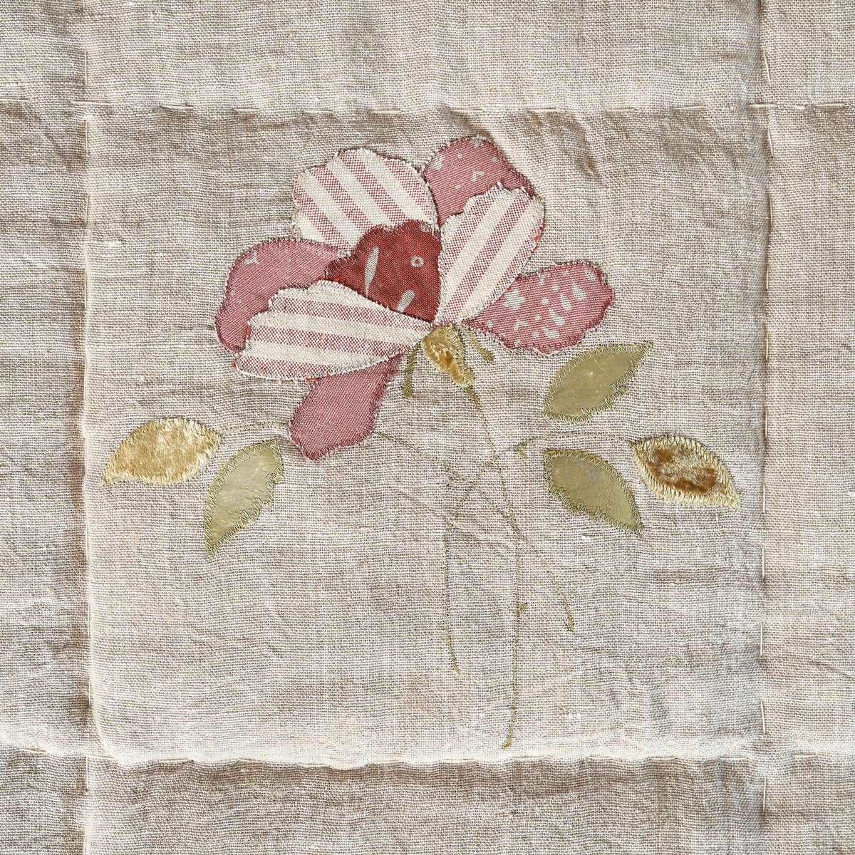 Close view of an appliquéd pink rose with stitched leaves