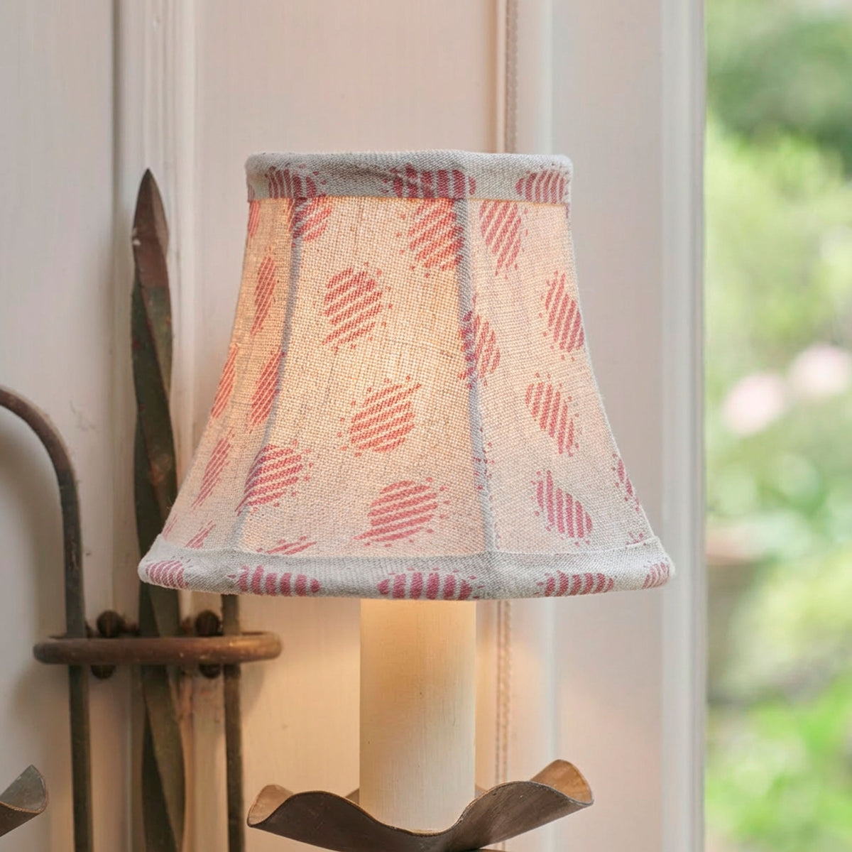 The same rose-printed wall shade lit, casting a warm evening glow