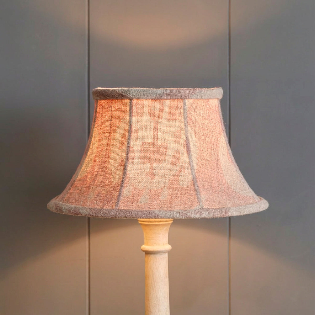 The same Sacha framed lampshade lit, glowing warm against grey boards