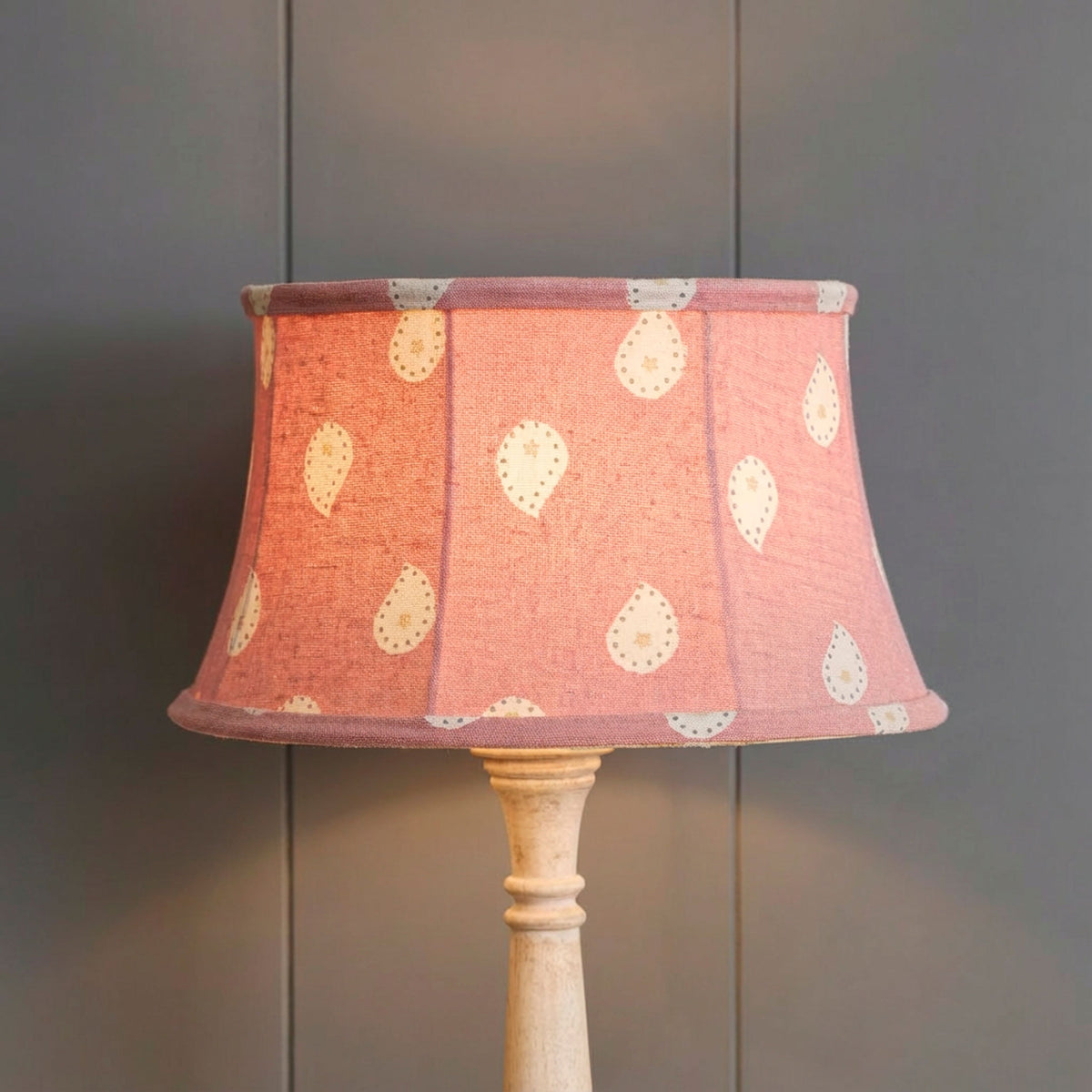 Lit Rose Mika framed lampshade glowing warm against grey panelling