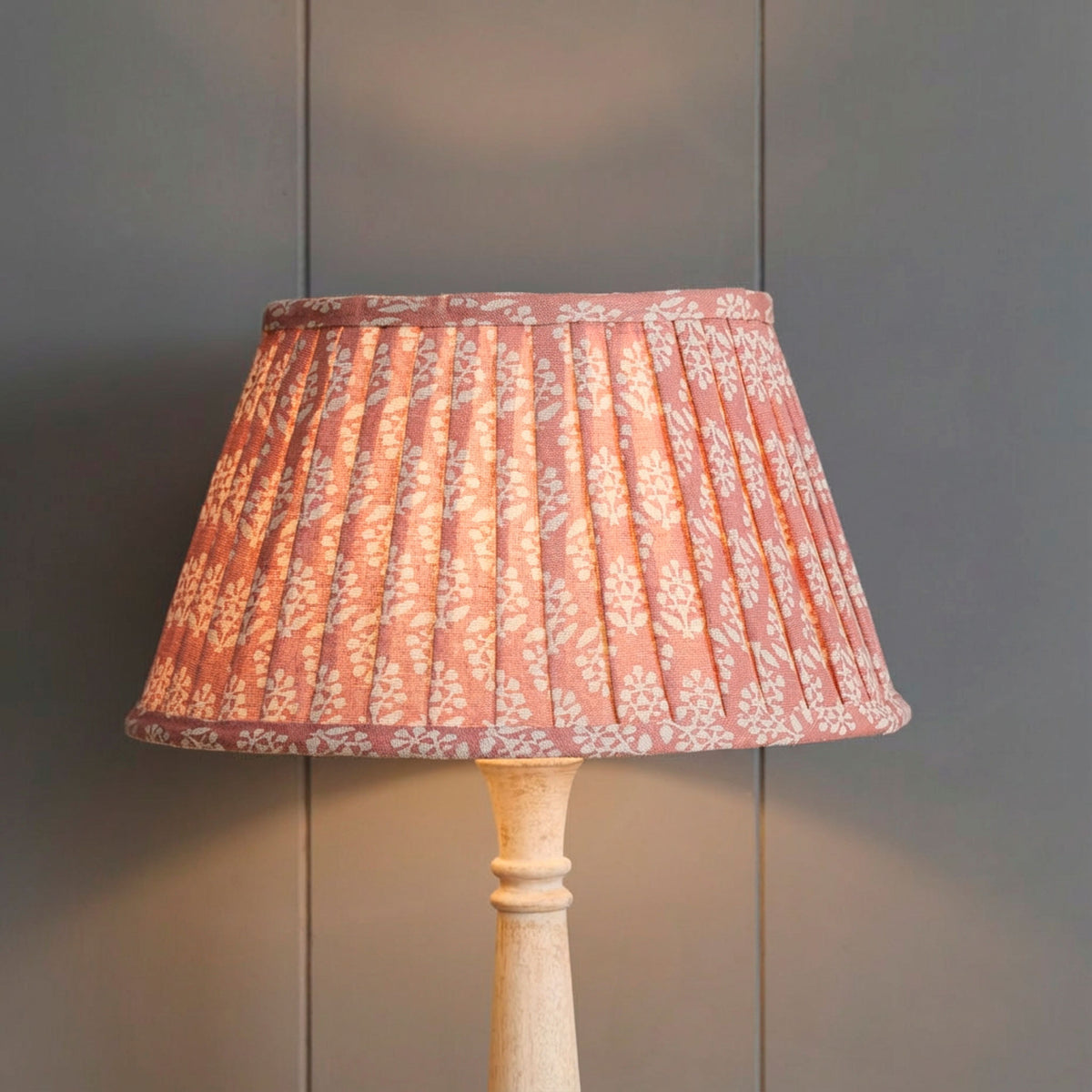 Rose Sprig pleated lampshade lit against grey panelling