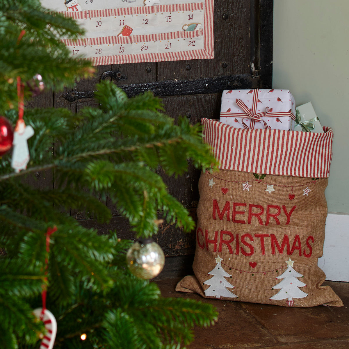 Christmas sack propped beside a decorated tree with wrapped parcels