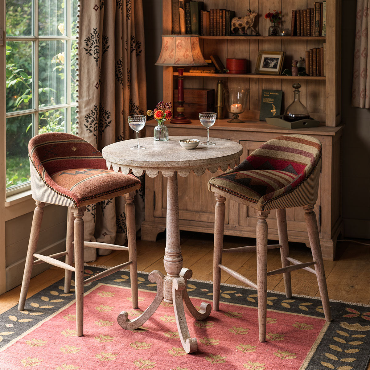 Bistro table with two velvet bar stools in a panelled room