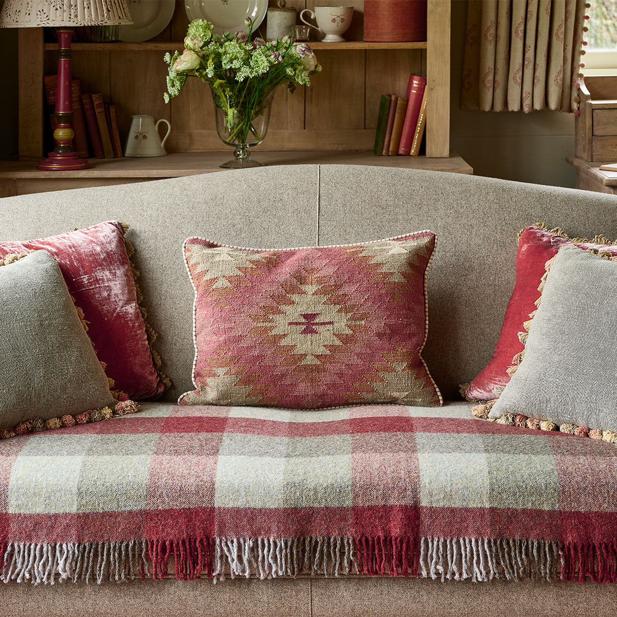 Ragini kilim cushions along a checked sofa in front of a bookcase