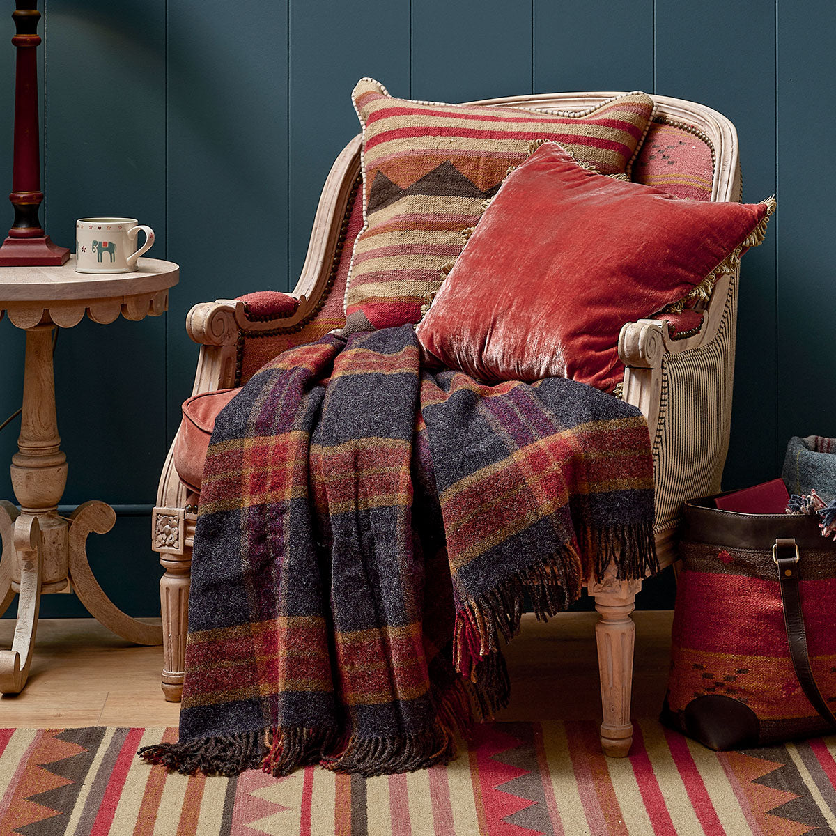 Tartan wool throw over a day bed with red cushions in a blue room