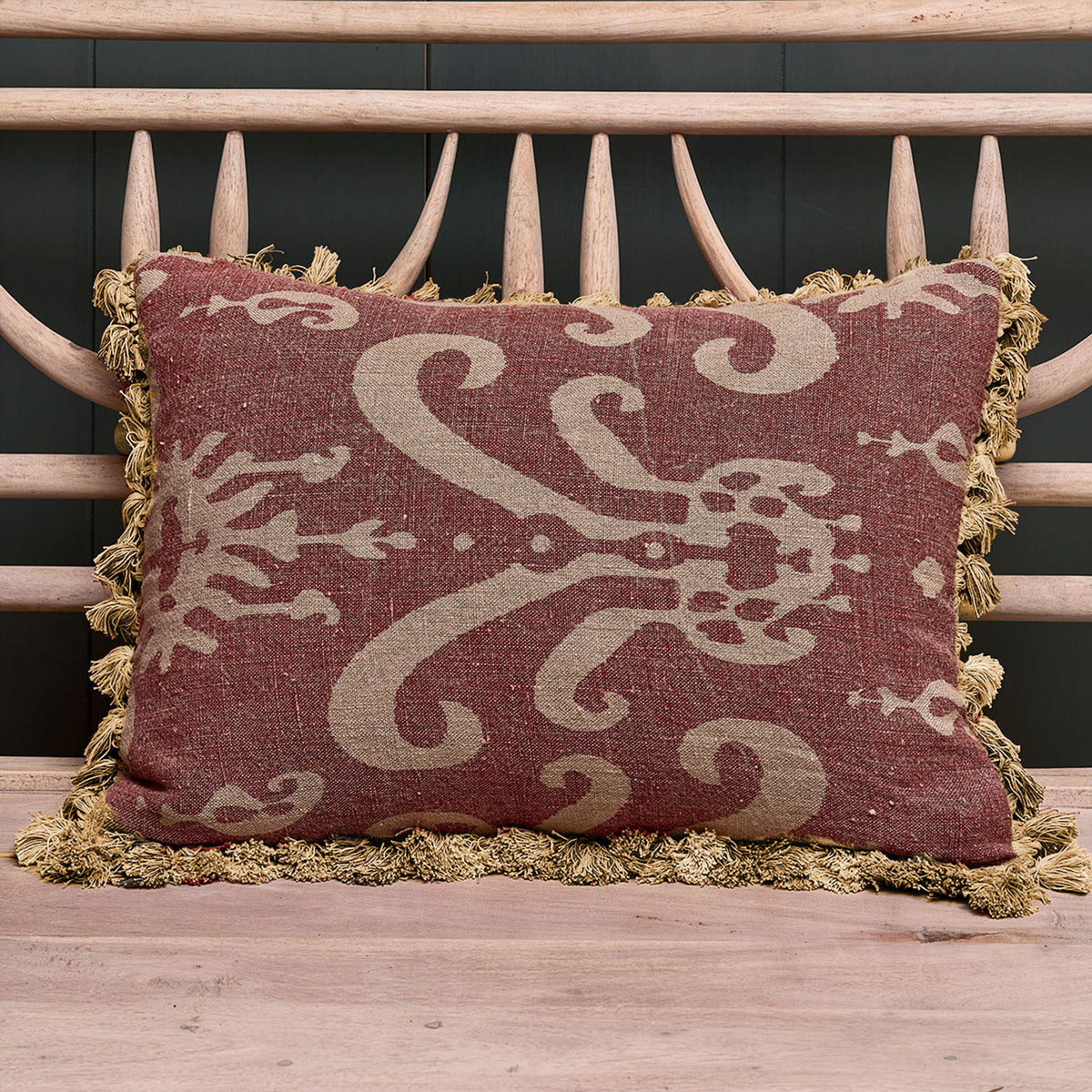 Damson Sacha rustic linen cushion with tassel trim on a rustic bench
