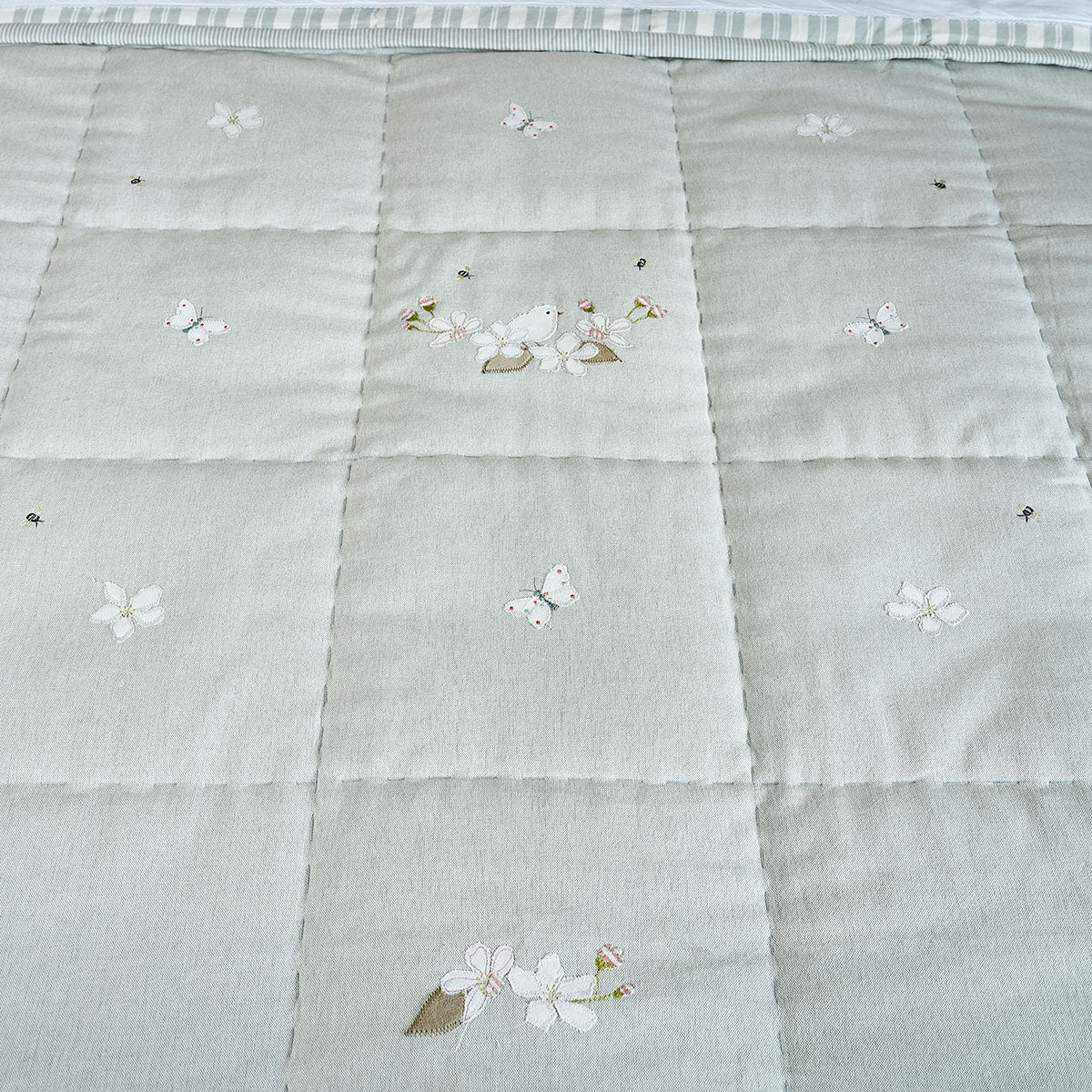 Duck egg quilt showing embroidered blossom and bees across the squares