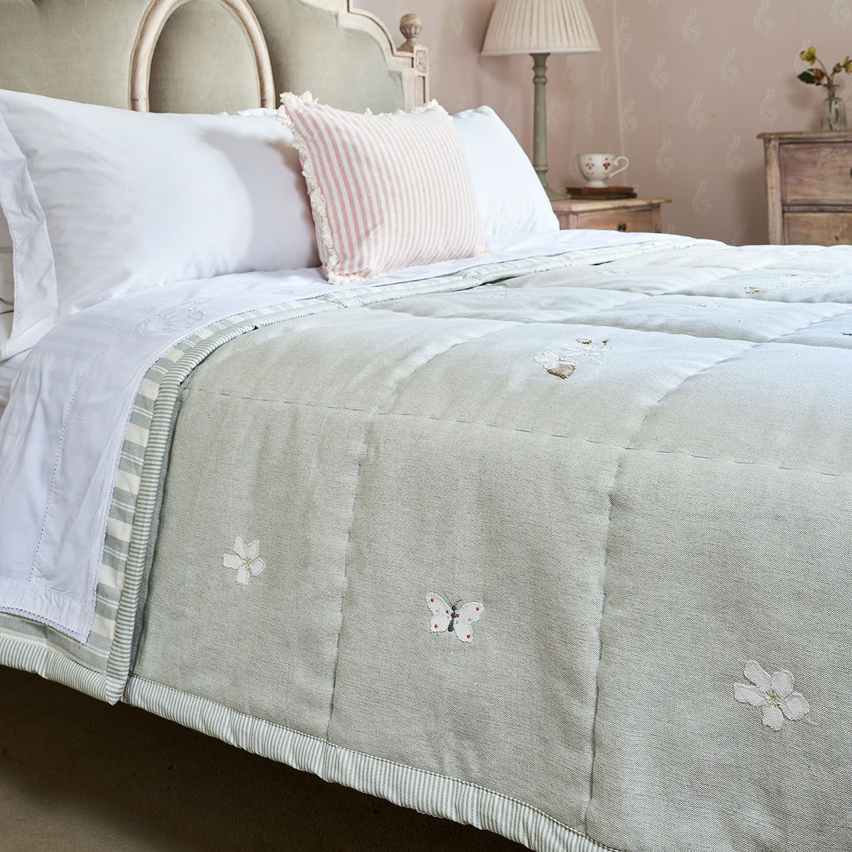 Duck Egg Apple Blossom quilt on a bed with pink and white pillows