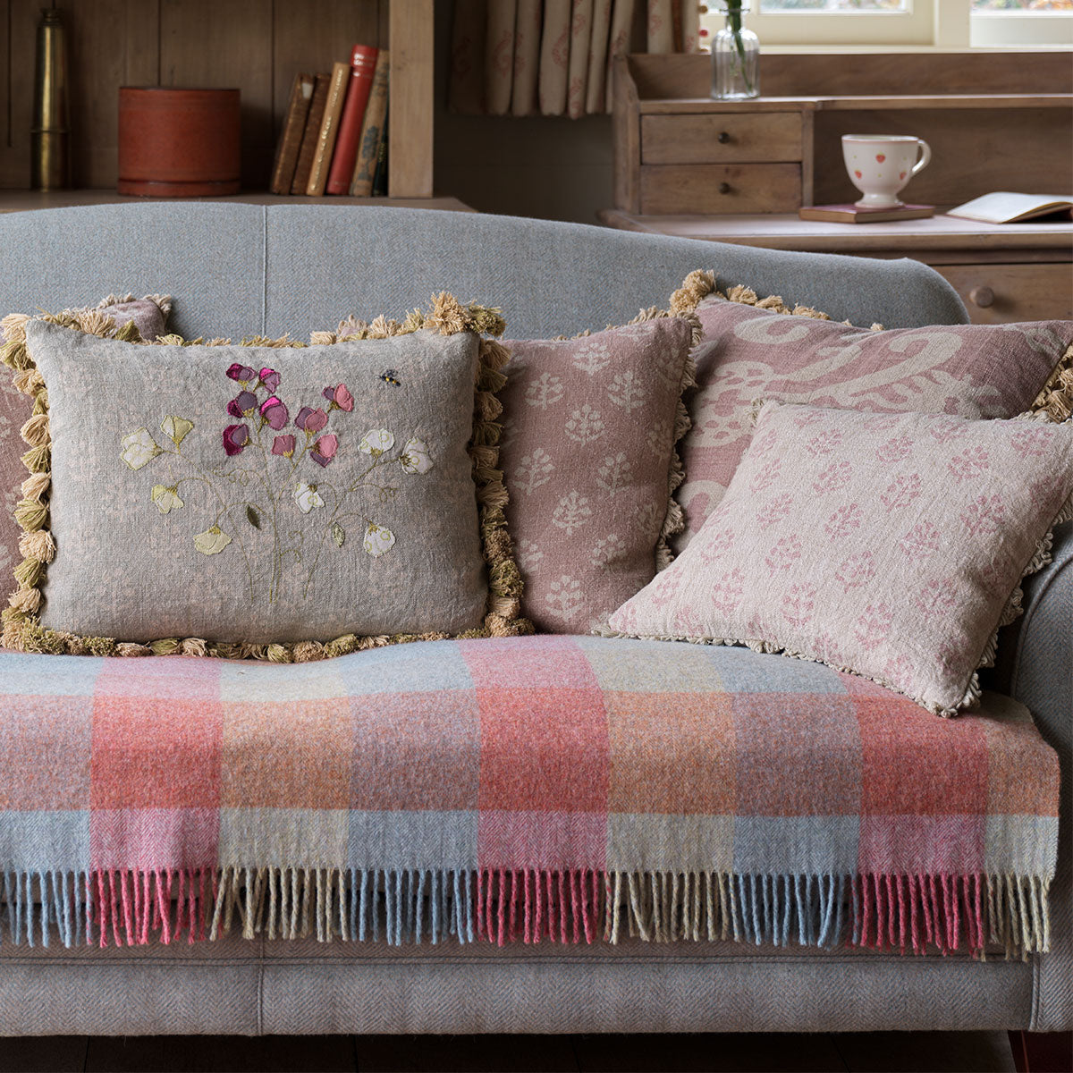Megha cushions arranged on a sofa with a pink checked wool throw