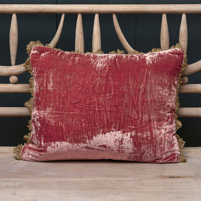 Dusky rose crushed velvet cushion with tassel trim on a painted bench