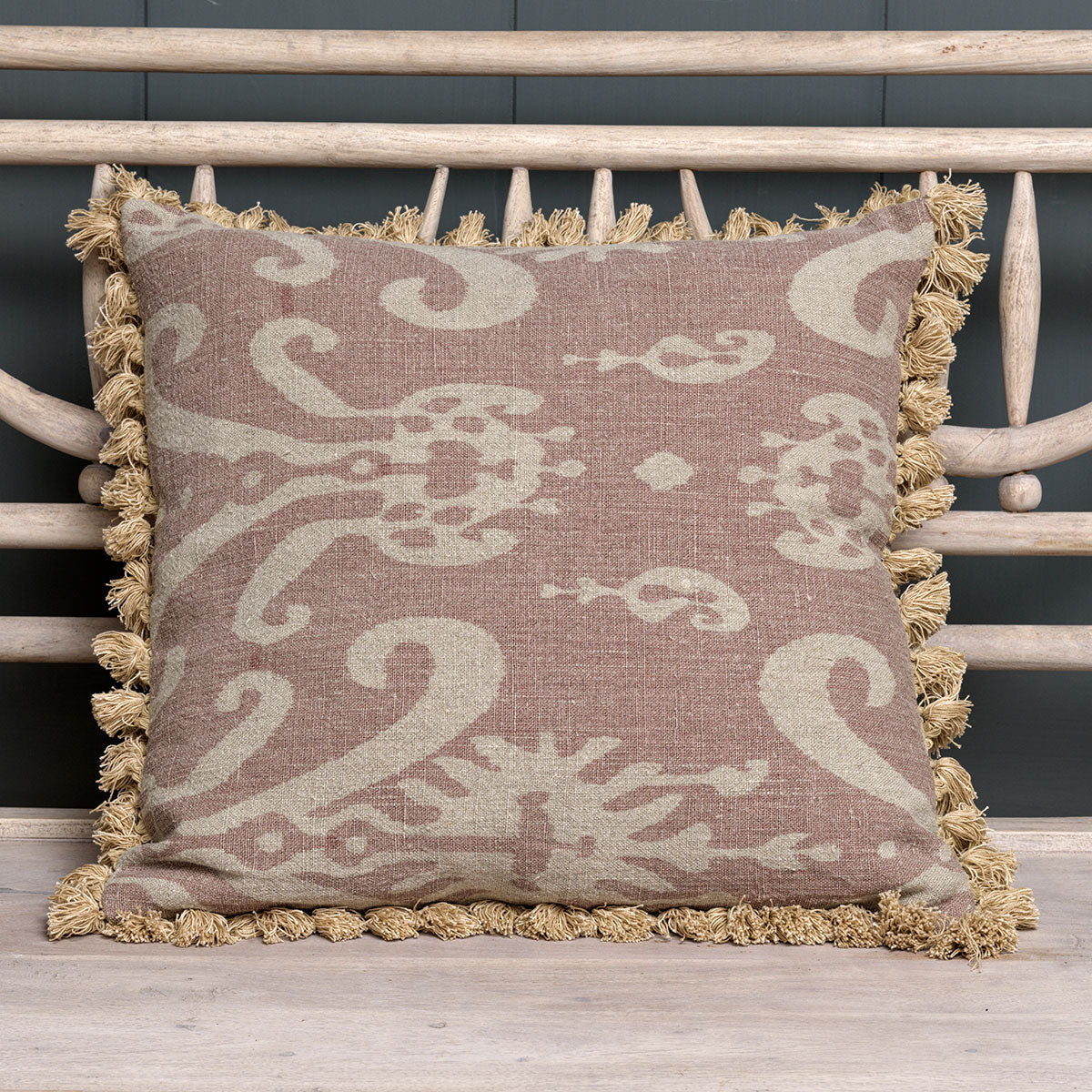 Dusky mauve Sacha linen cushion with tassels against wooden slats