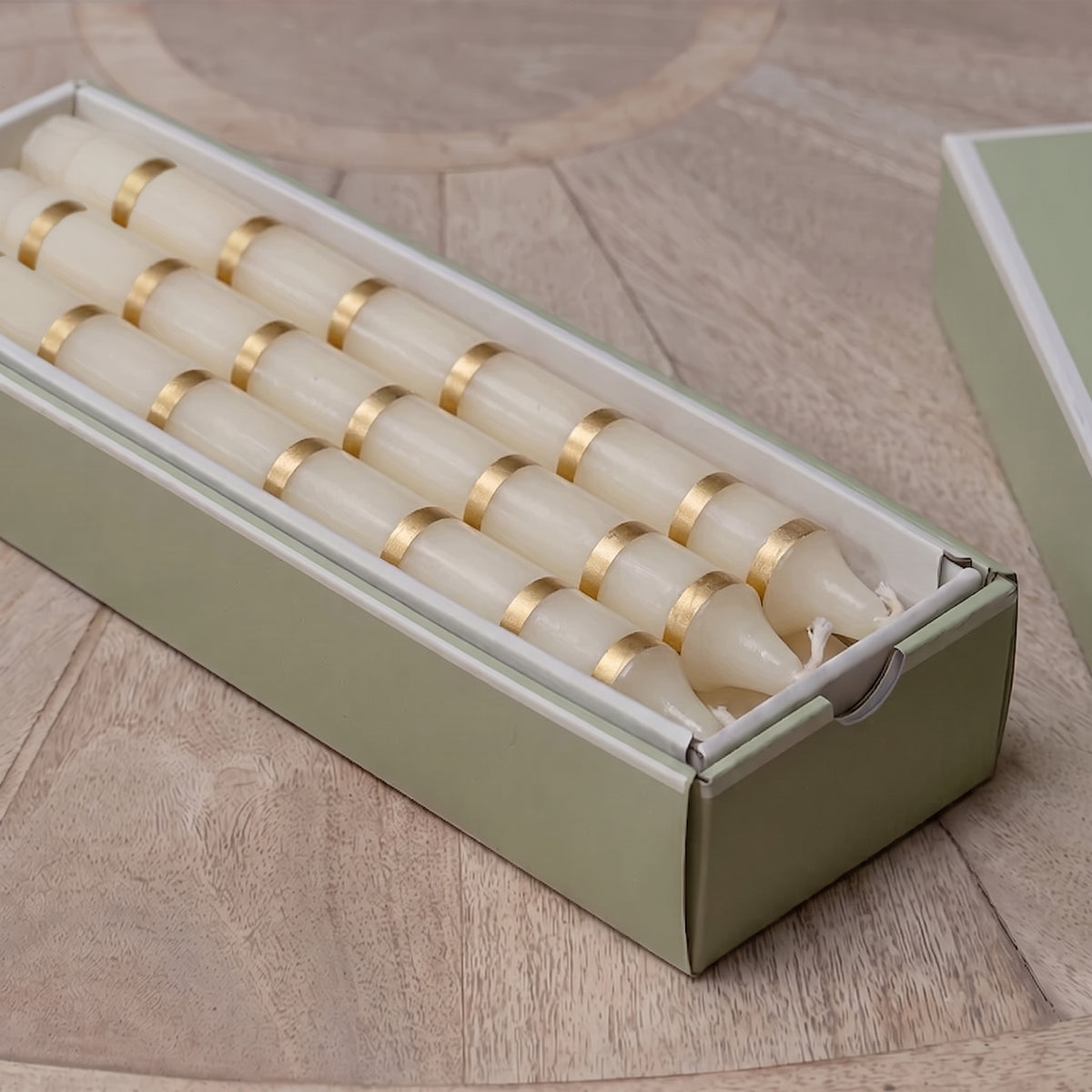 Gold thin stripe hand-painted candles laid in their green presentation box