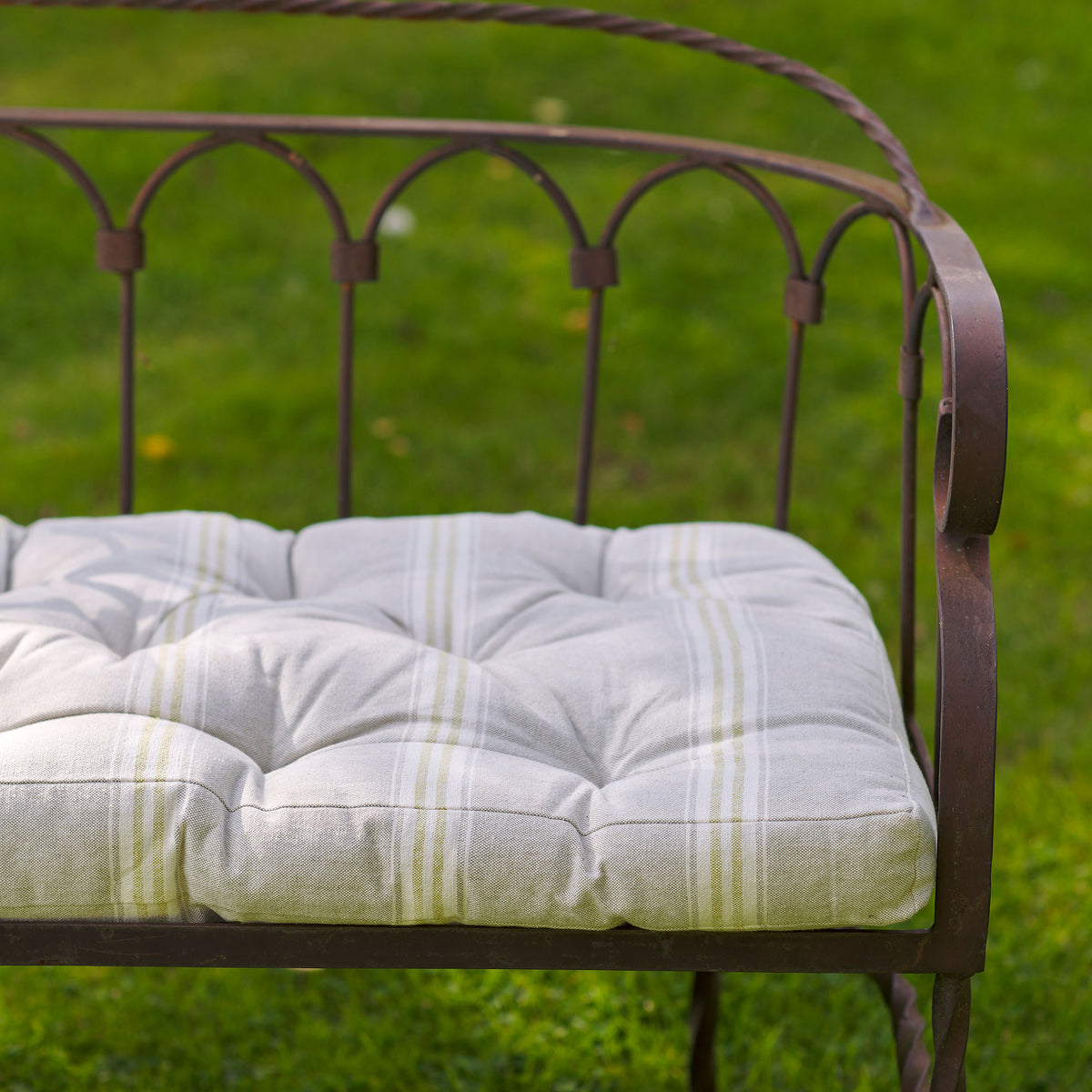 Green Gustavian stripe bench cushion on a metal bedstead-style bench