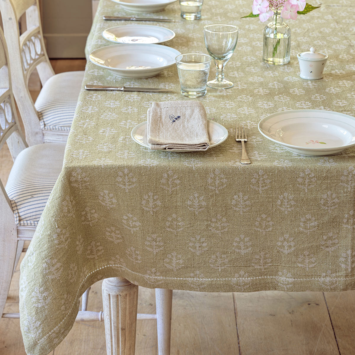 Green gold Megha rustic linen tablecloth on a long table with painted chairs