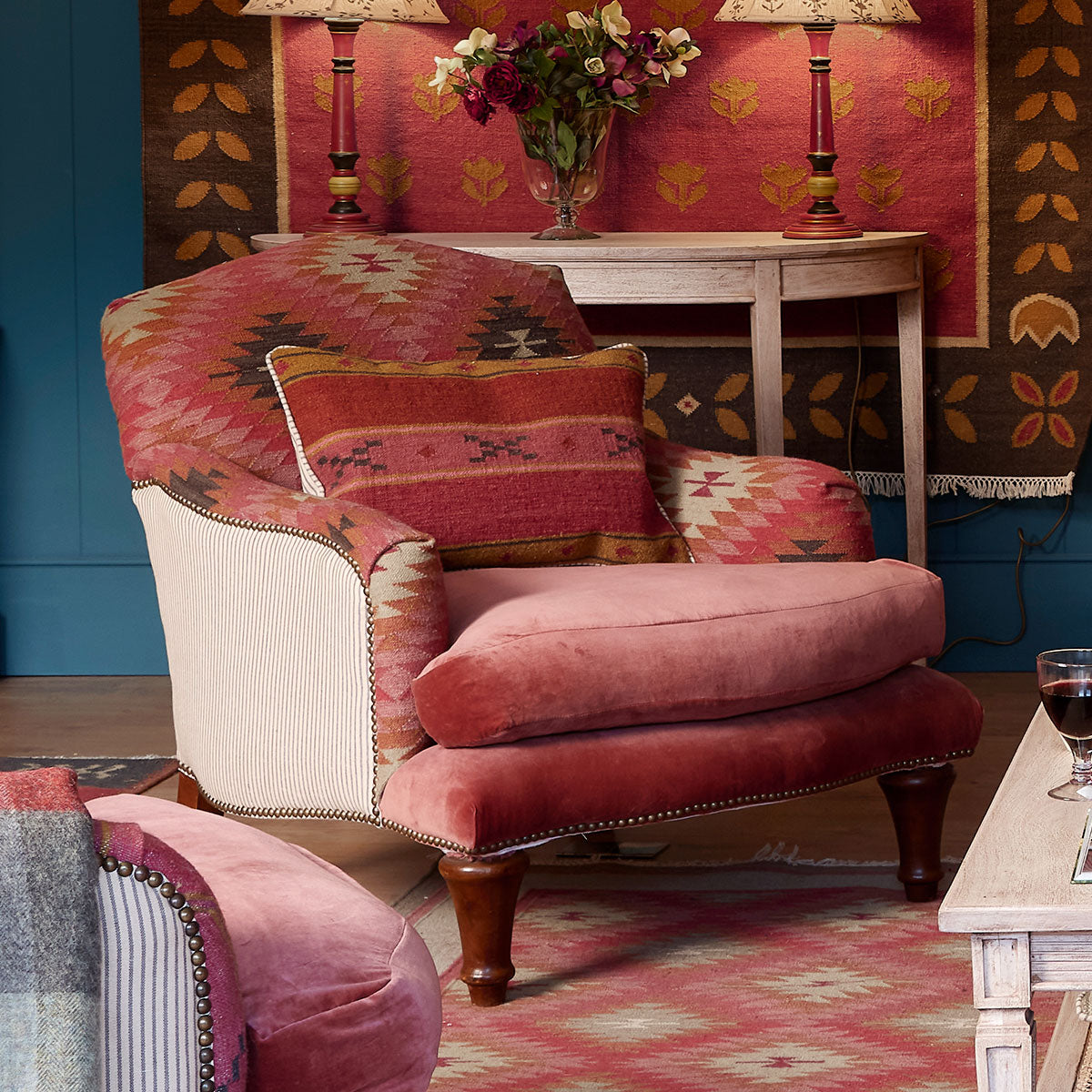 Howard chair in kilim and velvet beside a table in a blue panelled room