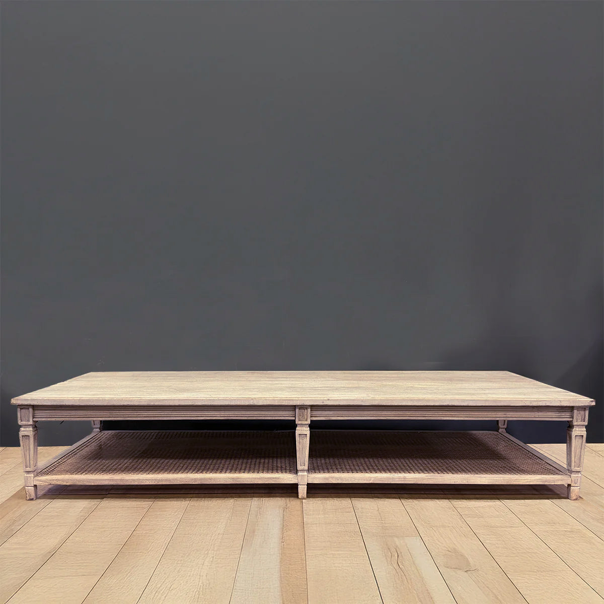 Extra large caned coffee table photographed plainly against grey