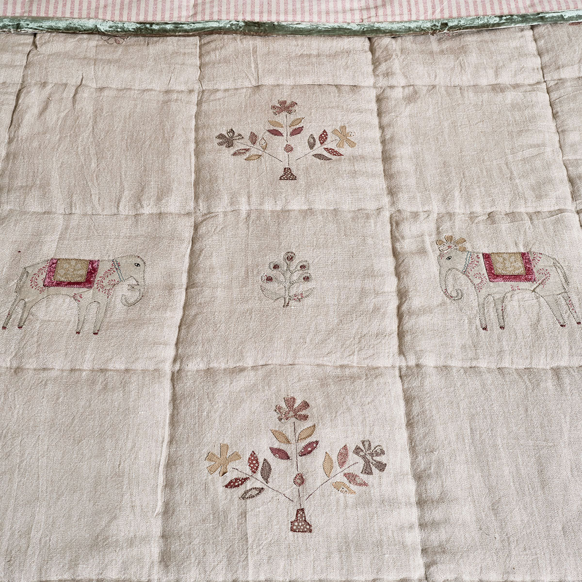 Close view of embroidered elephants and floral sprigs on natural linen