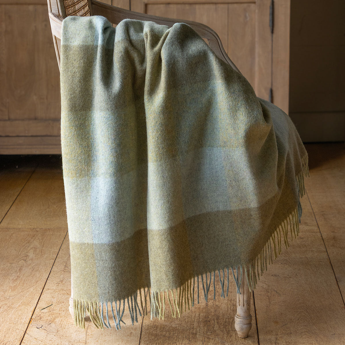 Evening seas harlequin Shetland wool throw draped over a wooden cupboard