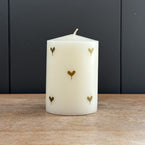 Gold heart scented pillar candle with hand-painted hearts, seen closely