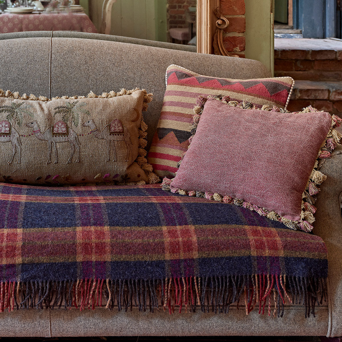 Red Earth tasselled cushions on a daybed with tartan wool throw