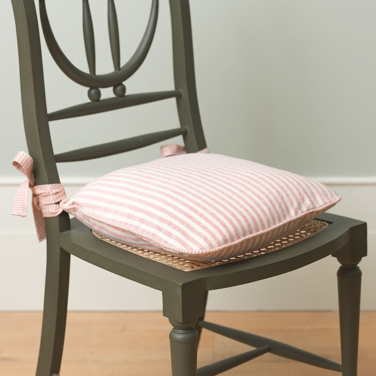 Red and natural striped seat cushion tied onto a painted dining chair