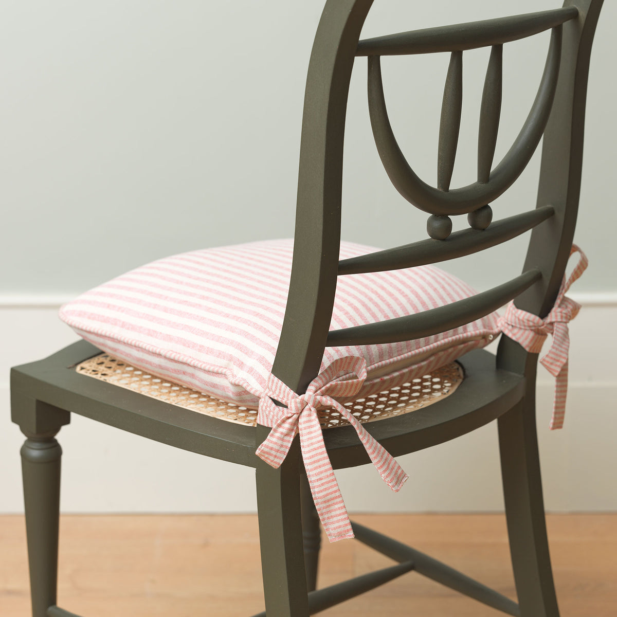 Striped chair cushion tied to a caned dining chair, side view