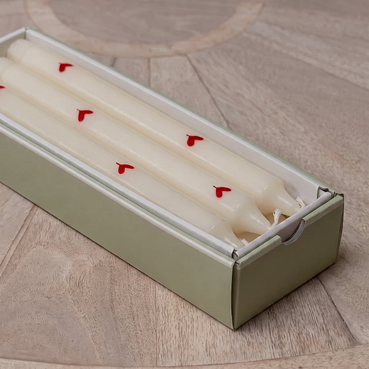 Red heart hand-painted candles nestled in their green presentation box