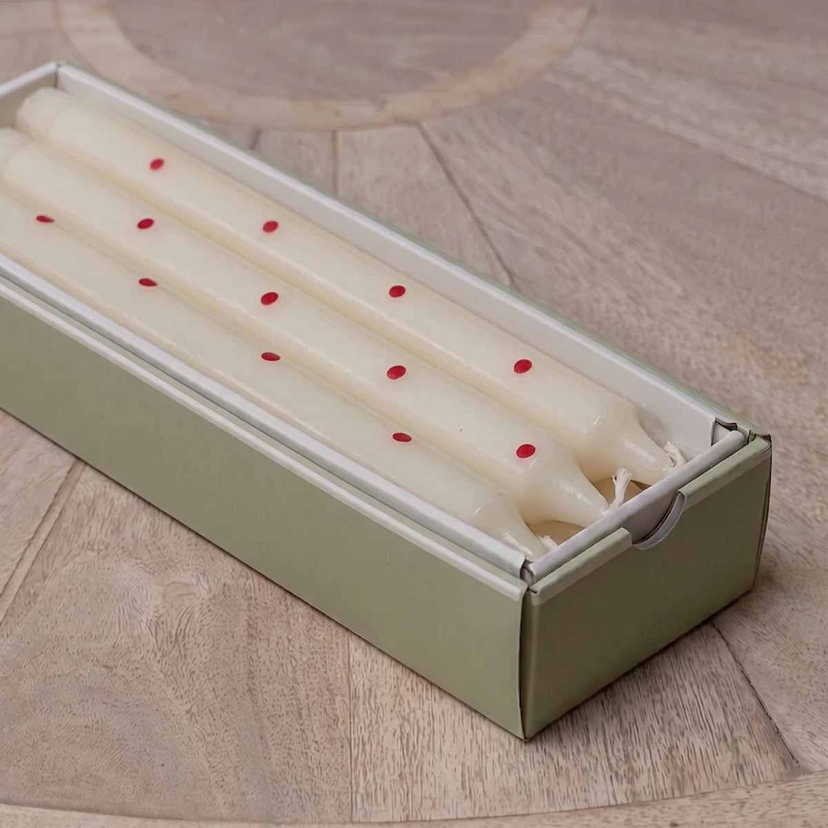 Red spot hand-painted candles laid inside their green gift box