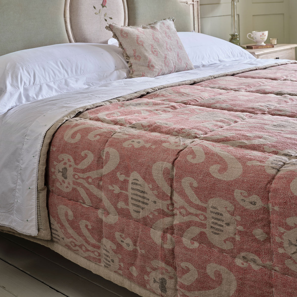 Rose charcoal Natasha quilt on a bed with a padded headboard