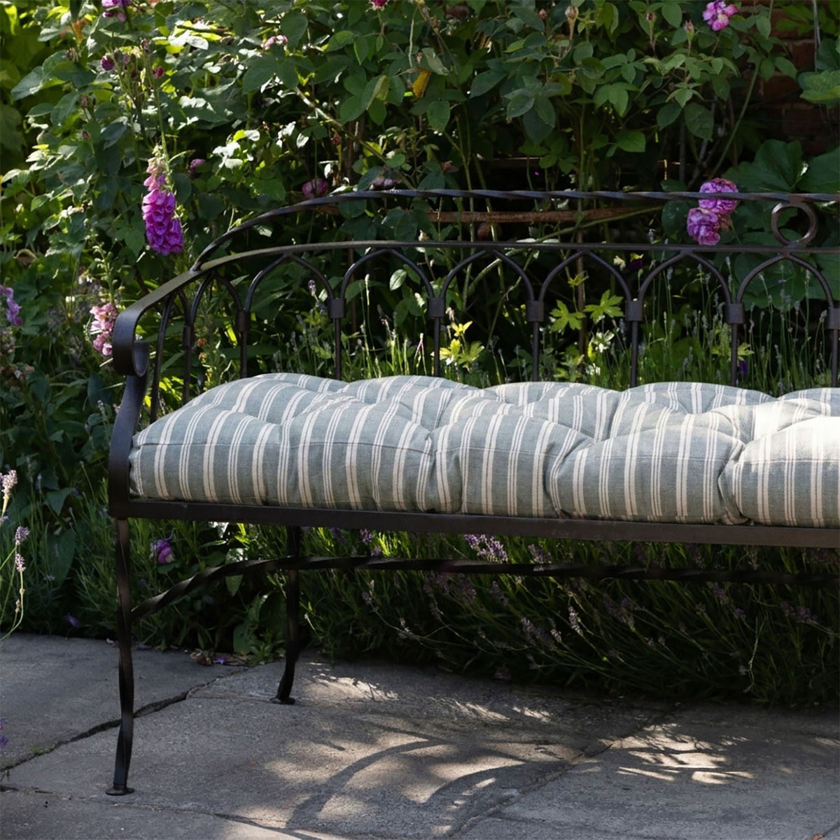Slate Cambridge stripe bench cushion on an iron bench among foxgloves