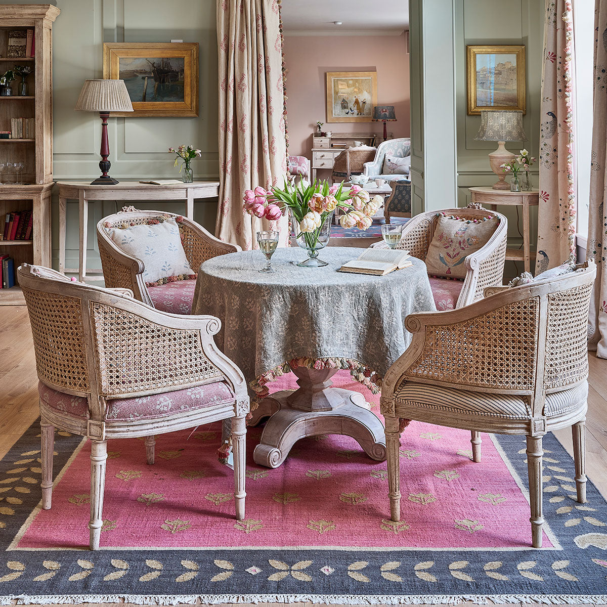 Dining room with the Megha tablecloth, cane chairs and a pink rug