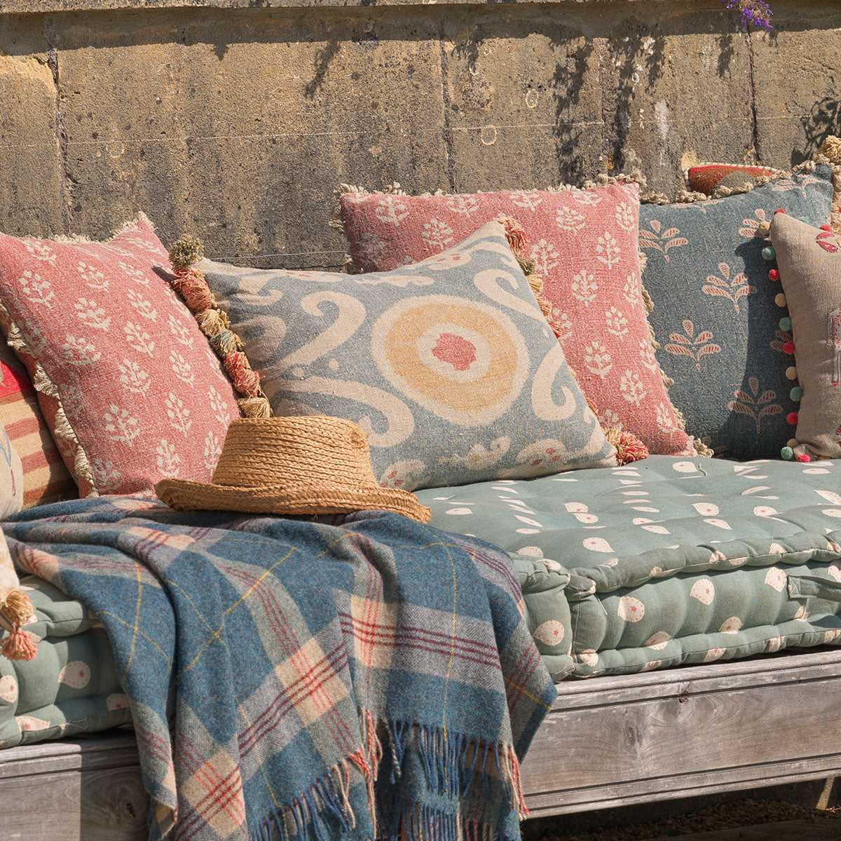 Bukhara cushions on an outdoor daybed with straw hat and throw
