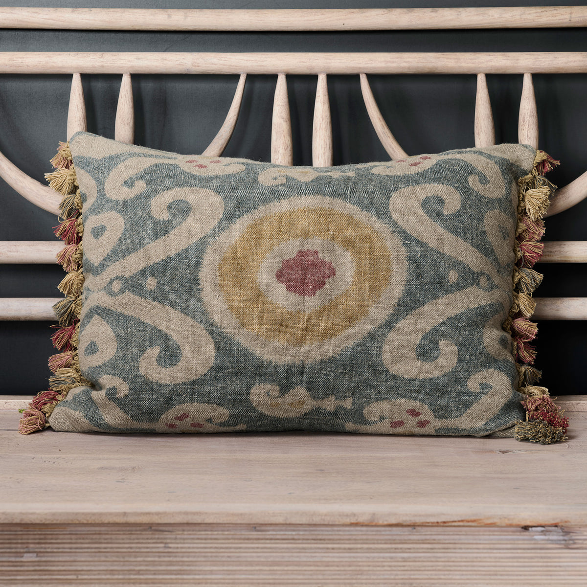 Summer Blue Bukhara linen cushion with tassel trim on a garden bench
