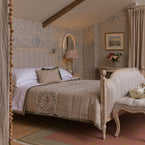 Maja papered bedroom with a four-poster bed under a sloping beamed ceiling