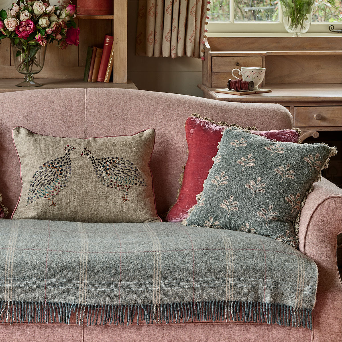 Reverse Leaf cushion on a pink sofa beneath a check wool throw