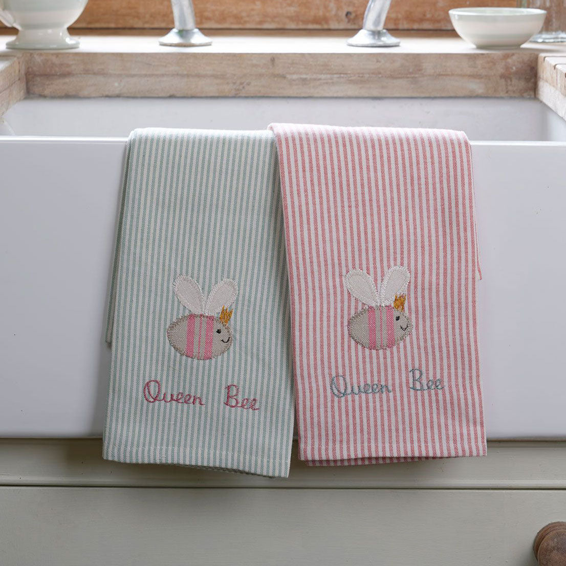 Queen Bee tea towels in duck egg and pink stripe on a windowsill