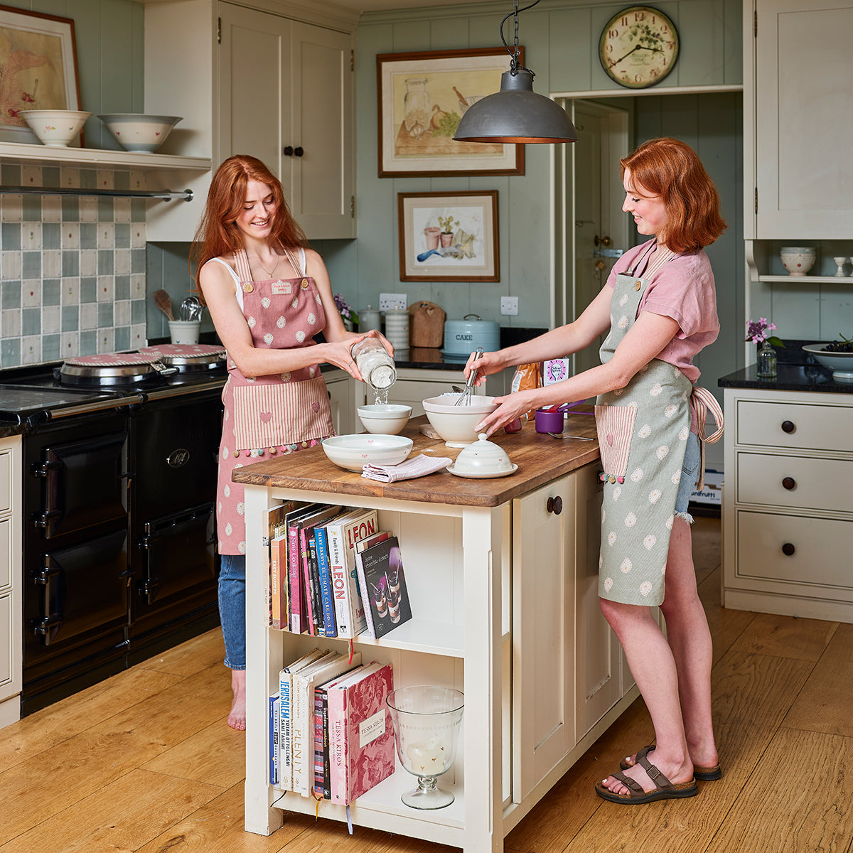 Two women in Mika aprons working together at a kitchen island