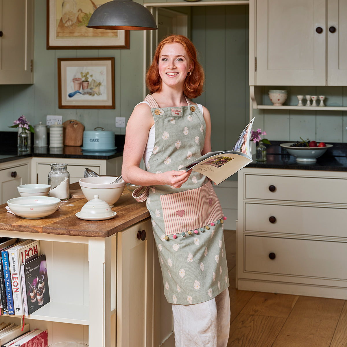 Woman in a duck egg Mika apron reading a recipe book