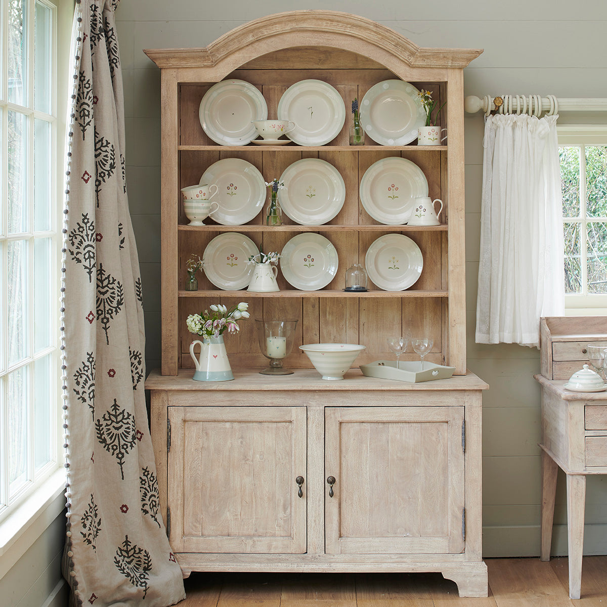 Curved top dresser displaying white china plates and bowls