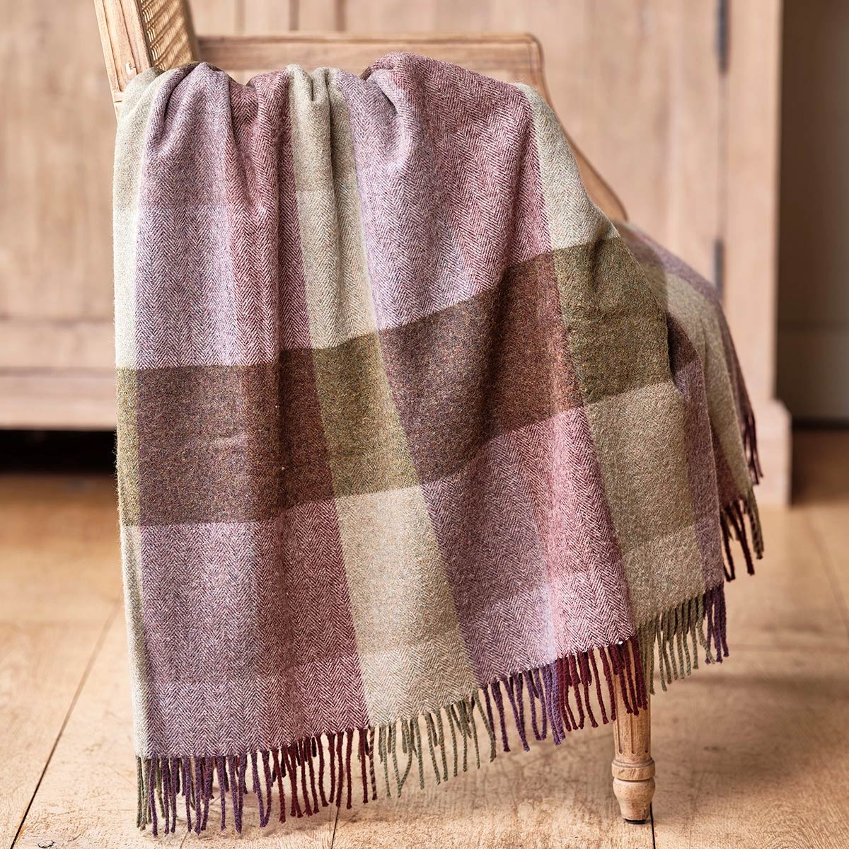 Violet Olive harlequin lambswool throw draped over a wooden chair
