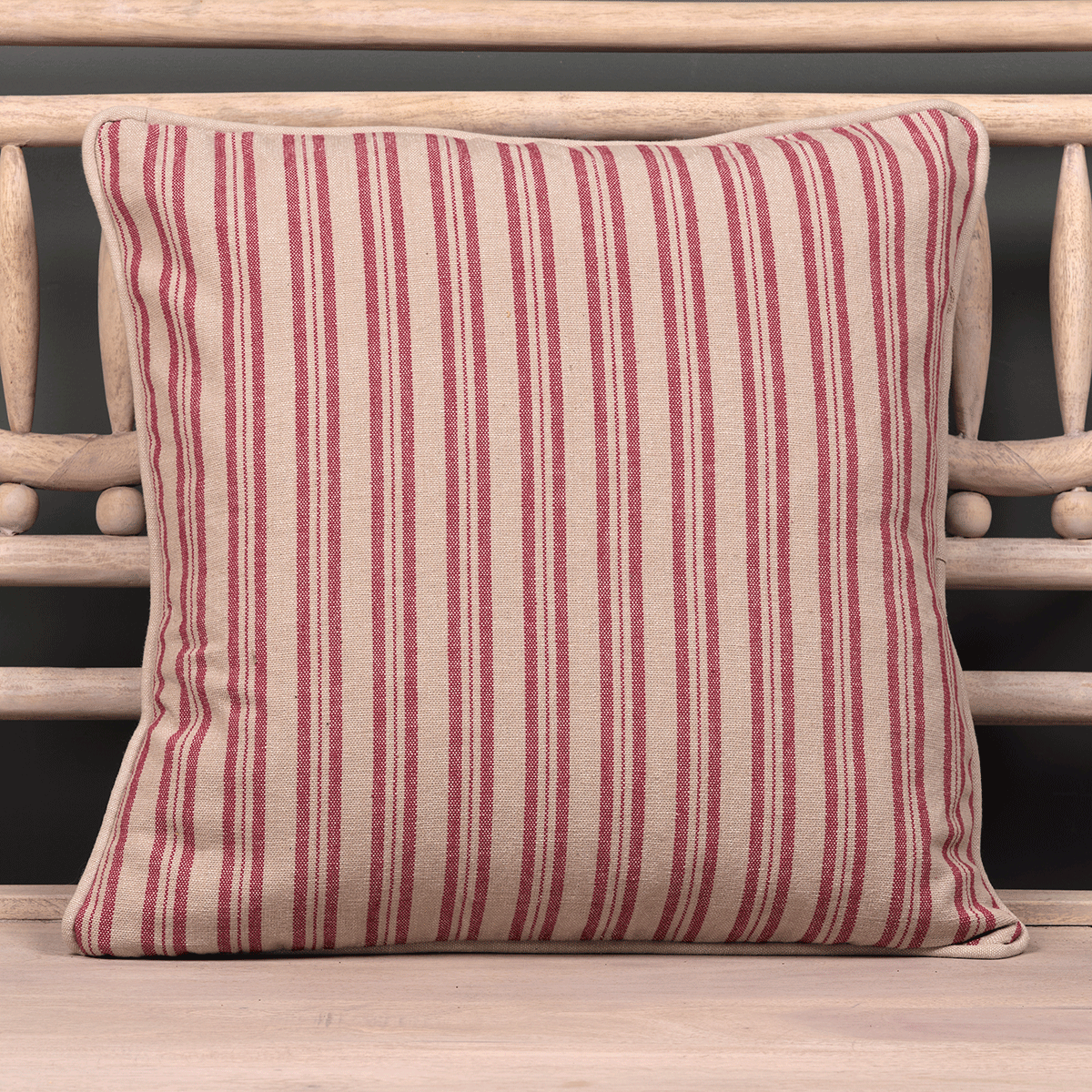 Sail red ticking stripe cushion with piped trim on a wooden bench